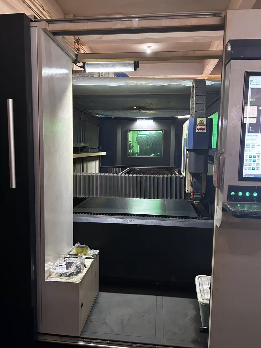 Enclosed laser cutting machine at Airwise factory — precision fabrication of HVAC sheet metal components including underfloor dampers and grilles